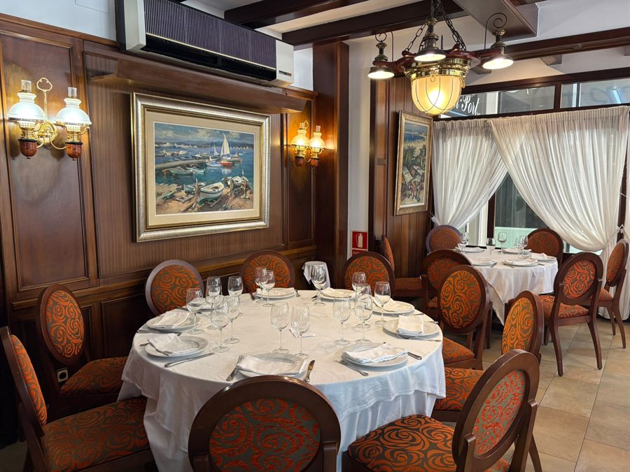 Sala interior de Bell Port con paredes de madera, lámparas de latón y mesa redonda vestida de blanco