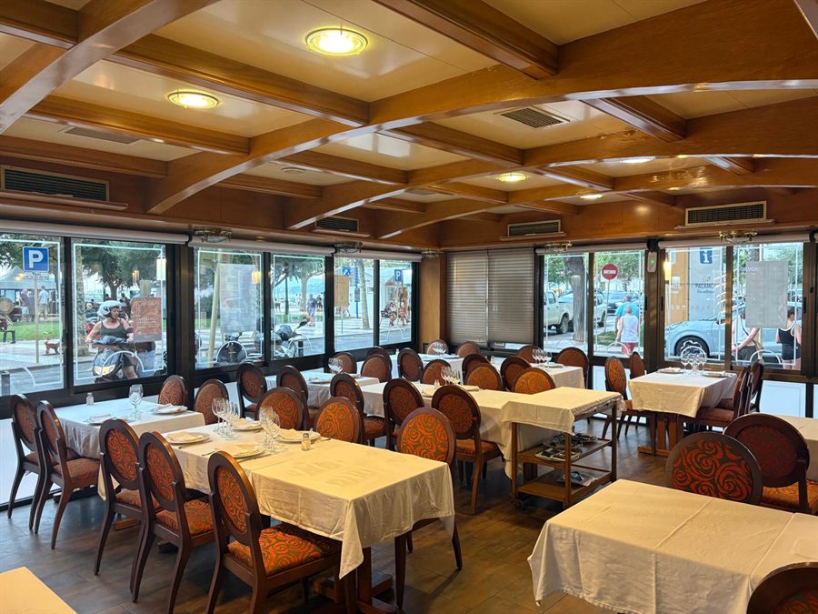 Terraza cubierta de Bell Port, con techo de vigas de madera y ventanales al paseo