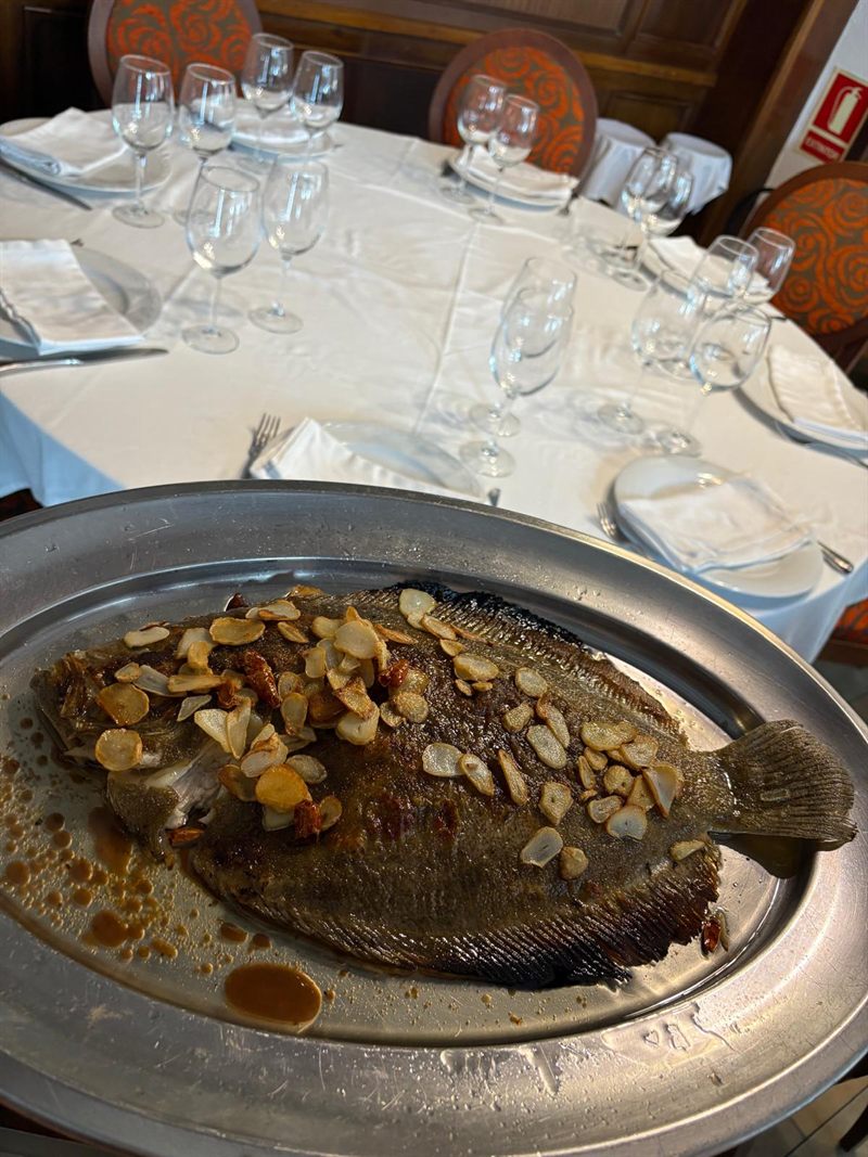 Rodaballo entero a la plancha con ajos laminados sobre bandeja de metal